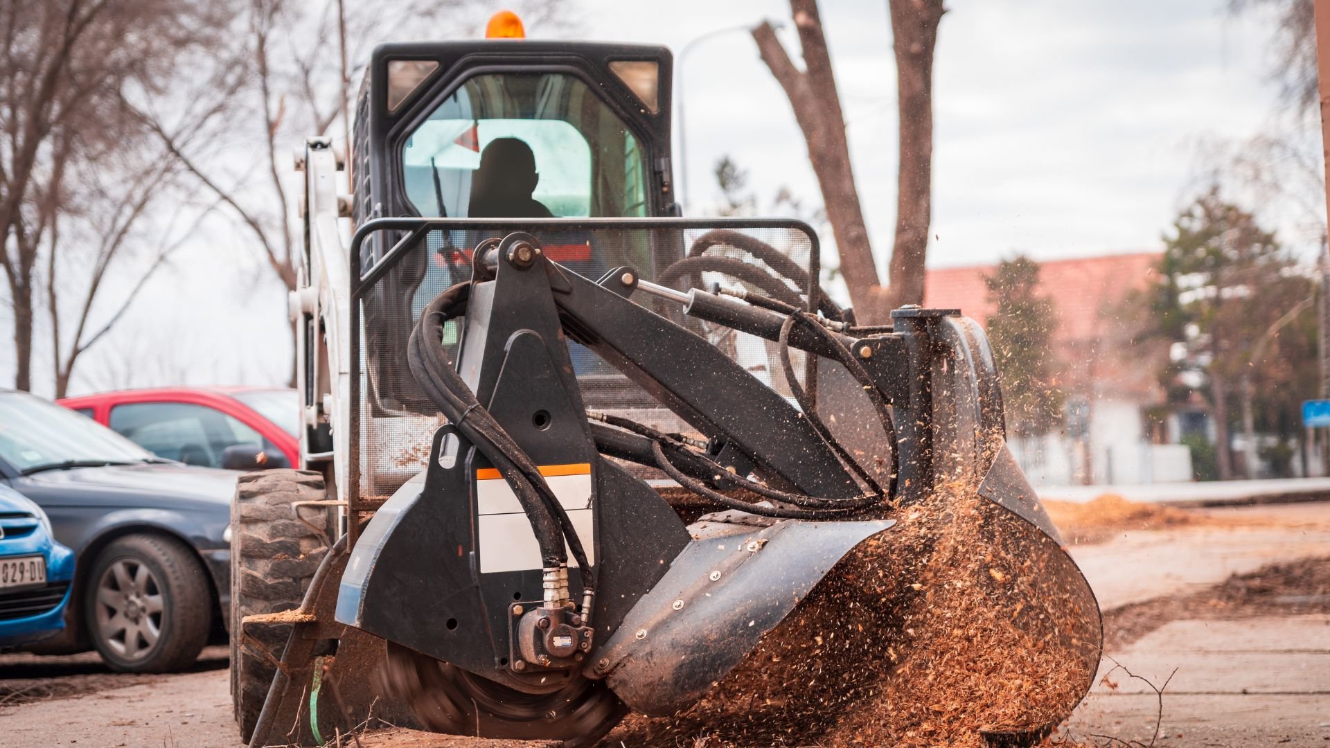 Skid steer loader clearing dirt and debris on urban street